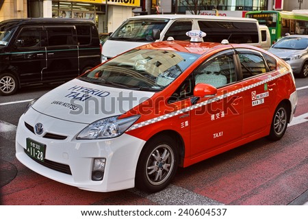 SHINJUKU, TOKYO - DECEMBER 27, 2014: Toyota Prius hybrid vehicle taxi, painted with orange and white. Photographed in the commercial district of Shinjuku, Tokyo.