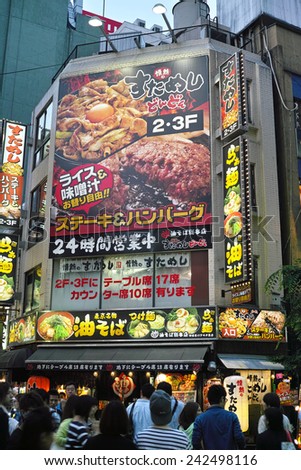 SHINJUKU, TOKYO - MAY 31, 2014: Street view of Shinjuku commercial district at night, billboards with neon light and crowd of pedestrians.
