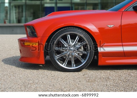 Bright red American muscle car with building in background