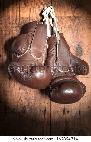 old Boxing Gloves, on wooden wall in the Spotlight