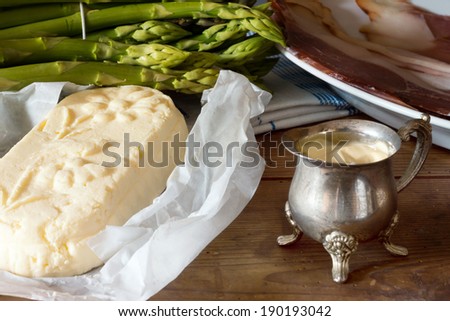 green Asparagus with Butter, Sauce Hollandaise and Ham on a wooden Table