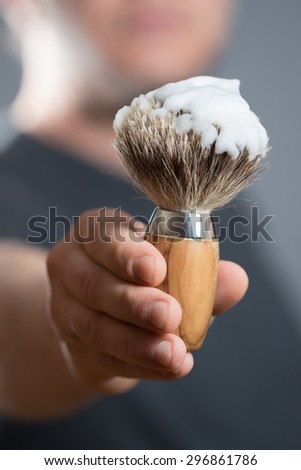Man is holding a Shaving Brush in his Hand
