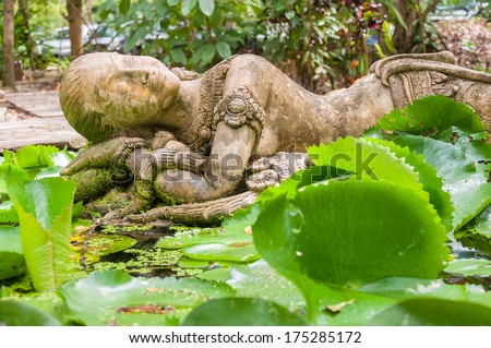 A Sleeping stone lady sculpture in Khmer style nearby lotus pond in public garden
