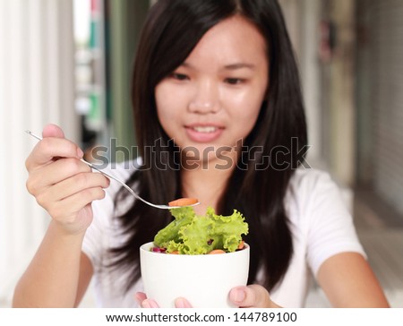 young lady eating vegetable salad at a restaurant