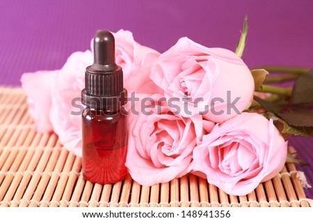One bottle of essential oil and rose flowers on bamboo mat, come on, let's go spa.