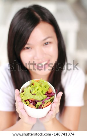 young lady holding a bowl of fresh salad