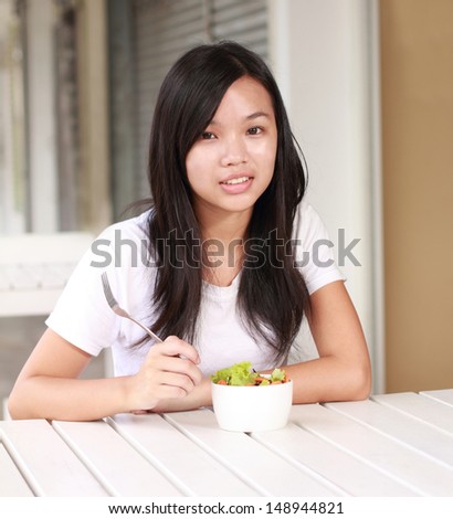 young lady eating vegetable salad at a restaurant