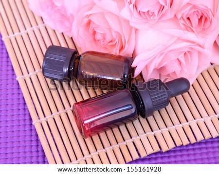 Two bottles essential oil and rose flowers on bamboo mat, come on, let\'s go spa