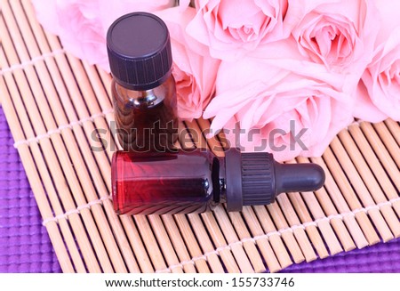 Two bottles essential oil and rose flowers on bamboo mat, come on, let\'s go spa.