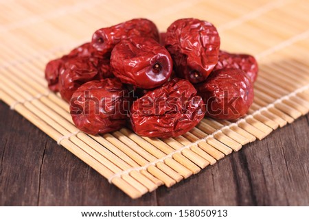 Dried chinese jujubes fruits with bamboo mat on wooden table