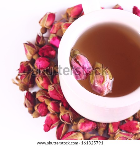 A glass of rose tea and dried roses on a white background