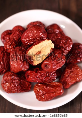 Dried chinese jujubes fruits with white plate on wooden table