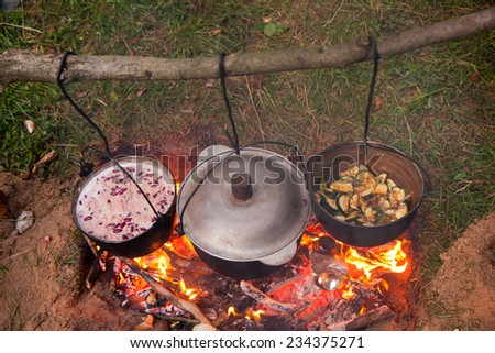 Cooking the meal in a kettle on the camp fire:River rafting expedition. Poland