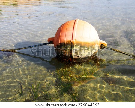 Huge red-orange buoys floating in  the warm water of the ocean.