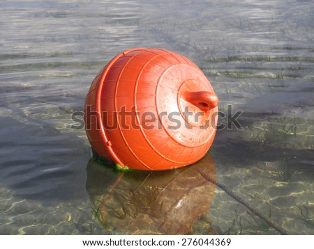 Huge red-orange buoys floating in  the warm water of the ocean.