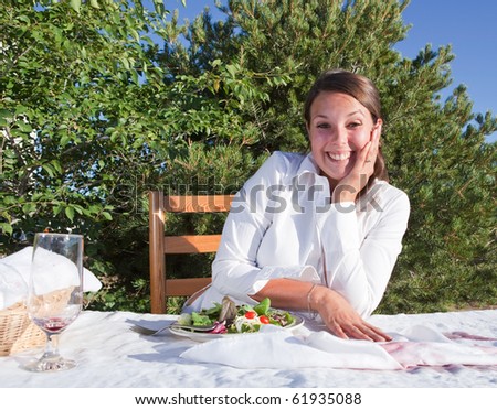 Embarrassed woman trying to cover wine that she spilled on white table cloth