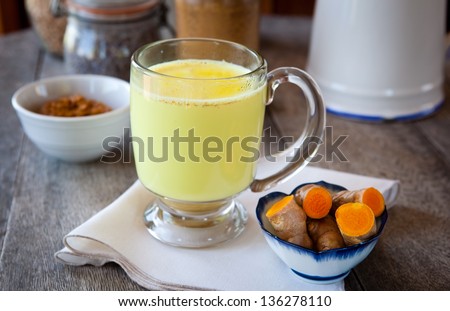 Golden milk. Turmeric herbal medicine, an anti-inflammatory. Shallow DOF, focus on the brim of the glass and the foam on milk