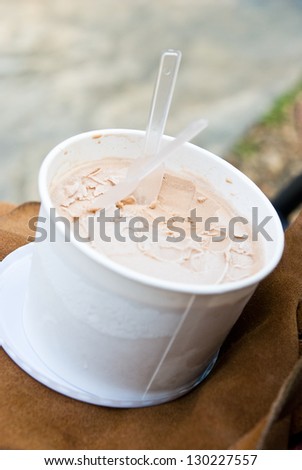 Homemade chocolate ice cream in paper cup on leather bag