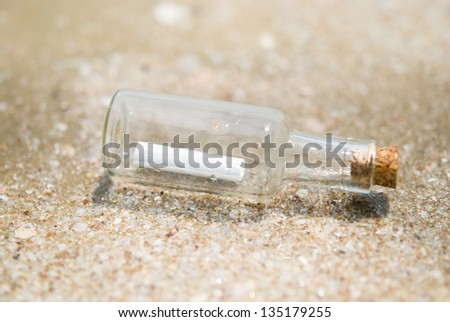Bottle with paper scroll place on sand