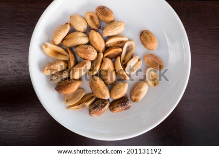 Salt roasted peanut in white plate on wooden table