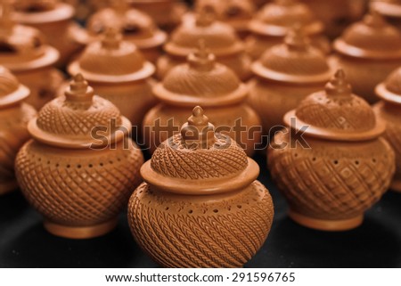 Beautiful clay pots with carved motifs in a row.