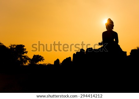 Buddha silhouette with light sparkling rays of the sun.