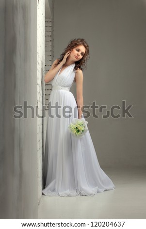 Beautiful girl in a wedding dress against a brick wall