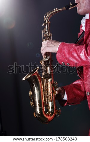 Adult man in red jacket playing the saxophone