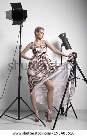 Beautiful blonde with short hair in a dress. posing in studio near light sources on a tripod