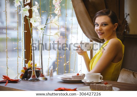 Portrait of a young girl sitting in a cafe and drinking coffee