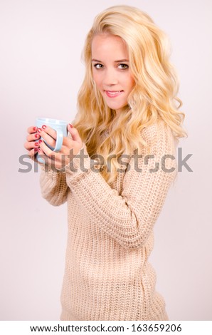 Beautiful fashionable girl in brown and gold clothes in winter and drinking tea.