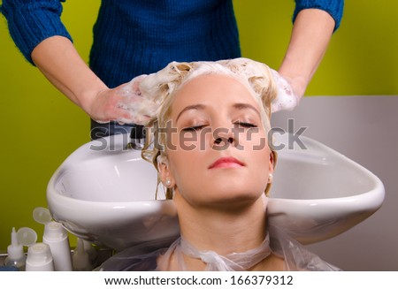 Hairdresser washing blond haired woman in the barber shop.