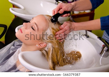 Hairdresser washing blond haired woman in the barber shop.