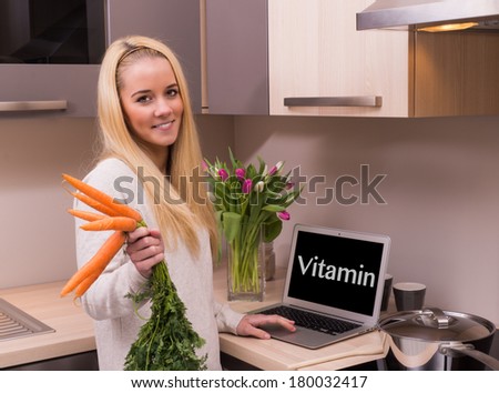 Woman with carrot and vitamin text on the laptop.