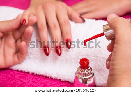 woman have nail coloring treatment in manicure salon