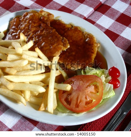 A plate of veal cutlets with fries and gravy.
