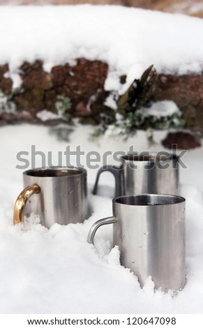 Three thermos cups in the snow on winter day