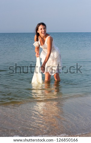 Young brunet woman in the water in wet white dress