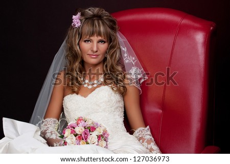blonde bride sitting in a red chair in the studio