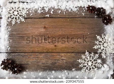 a snow frame with snowflakes and cones over wooden background, copy space
