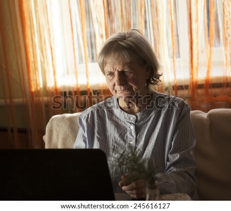 Old woman working on laptop computer at home, Grandma using notebook and searching on internet site
