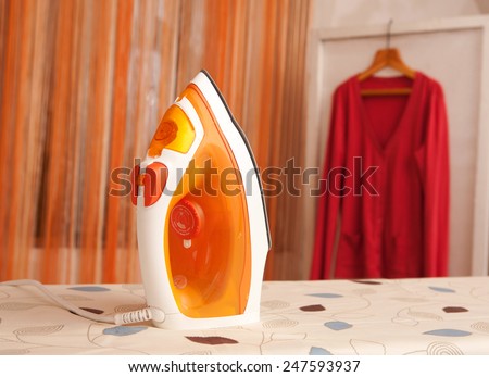 the orange iron clothes on ironing board