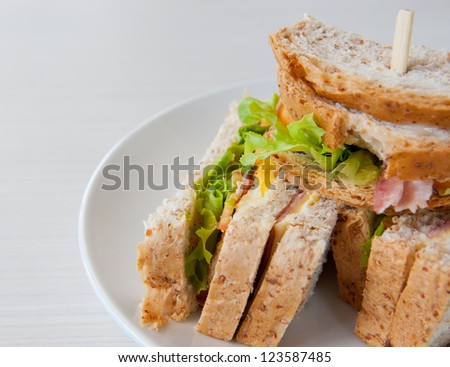 A club sandwich filled with  ham, bacon, cheese, lettuce and tomato.