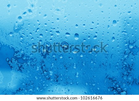 blue ice and water drops on winter glass