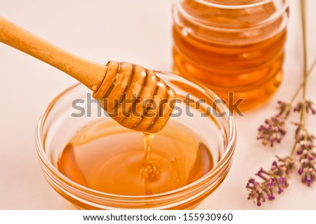 Bowl of lavender honey with wooden dipper drizzler and a jar and lavender in the background