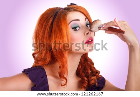 Glamour portrait of very attractive young woman with stylish make-up and ginger curly hair. Holding make-up brush.