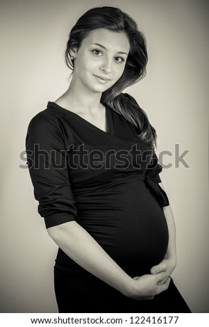 Shy pregnant woman in black dress. In black and white colors.