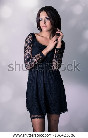 Very attractive young woman in black lace dress and black hose.