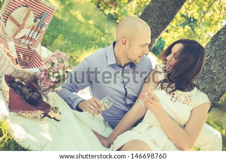 Happy young couple having a picnic in park under the tree.