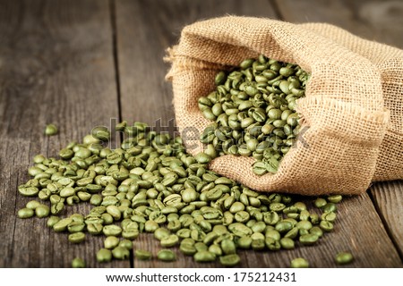 Green coffee beans in coffee bag made from burlap on wooden surface Focused in middle of the frame Green coffee beans in coffee bag made from burlap on wooden surface Focused in middle of the frame